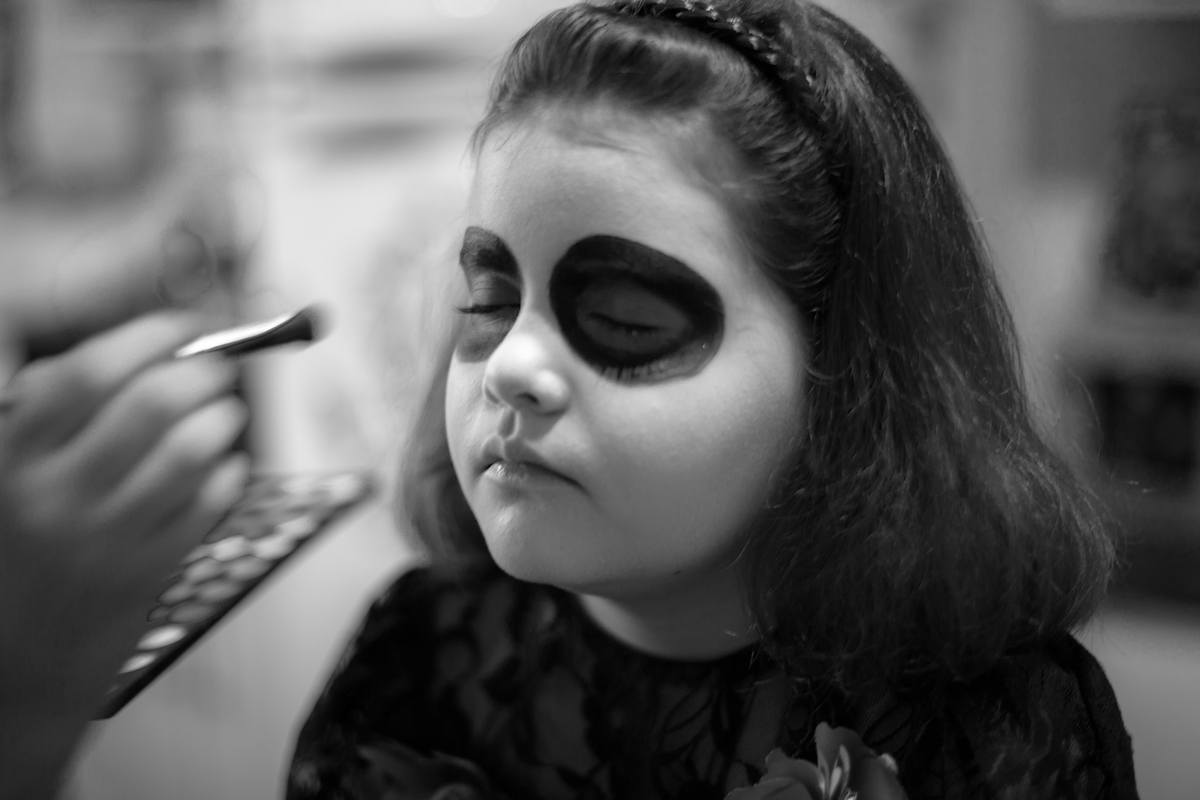 Foto em P/B, onde a criança está sendo maquiada para a sua festa de aniversário. 