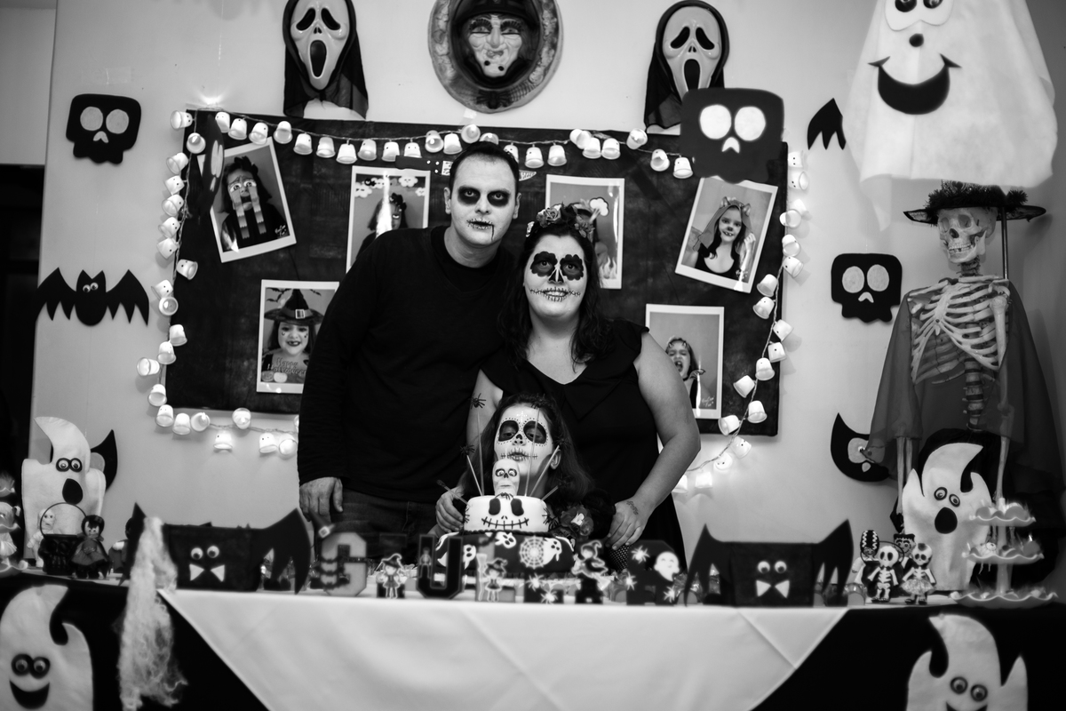 Foto em P/B da decoração e da mesa da festa de aniversário de Giullia Sampaio, onde ela posa com os pais.