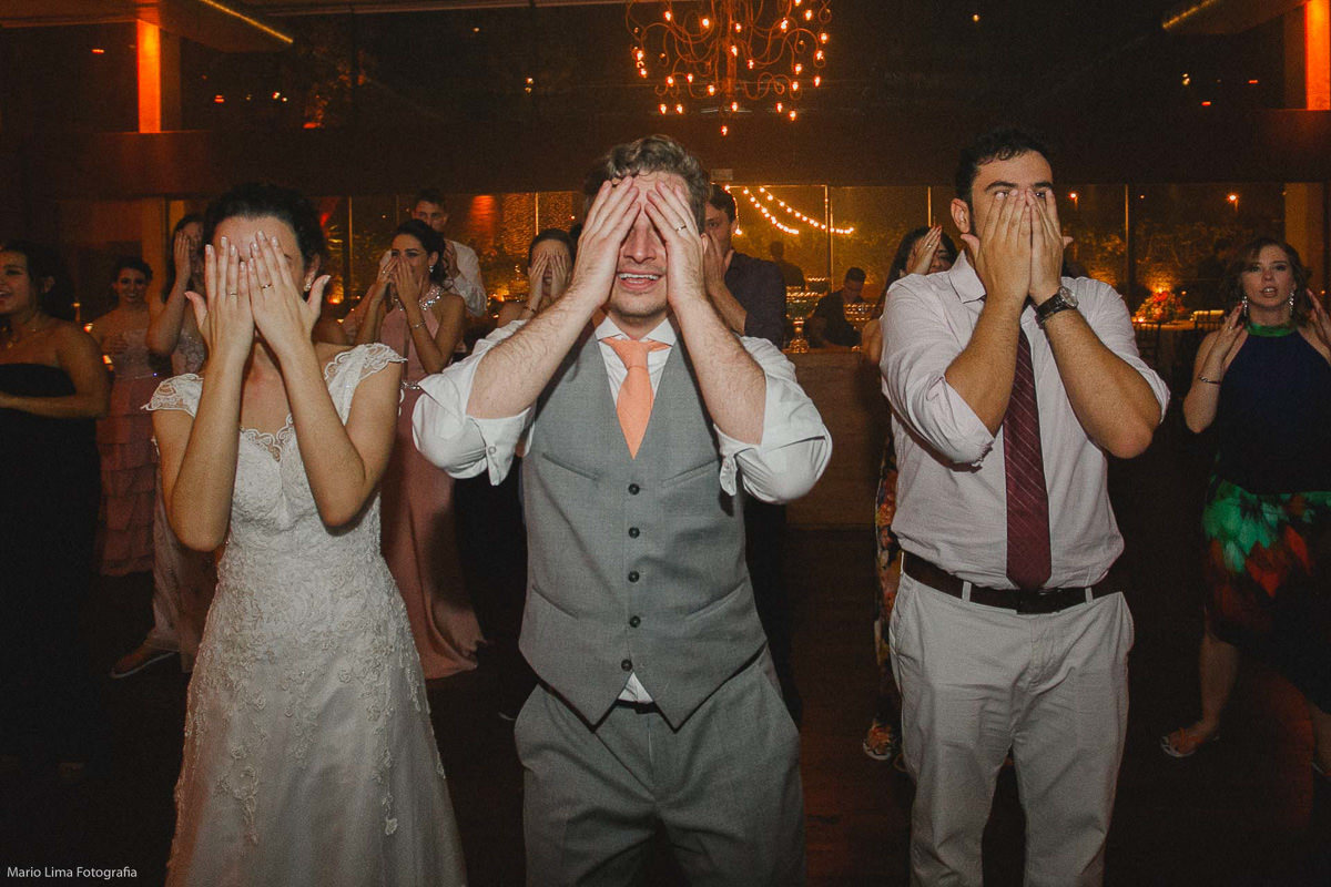 Noivos dançando com padrinho com os olhos fechados em festa de casamento na Casa Aragon