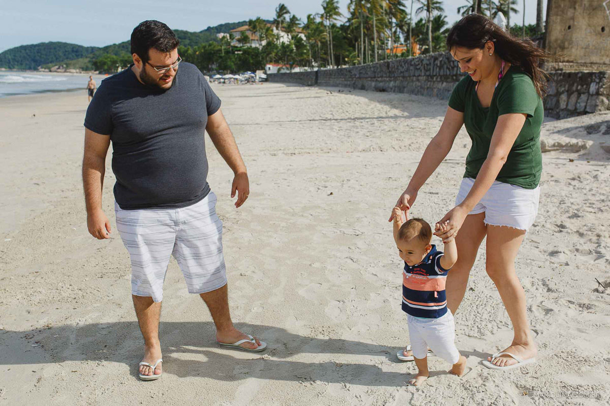 Bebê caminhando na praia do Guarujá com os pais