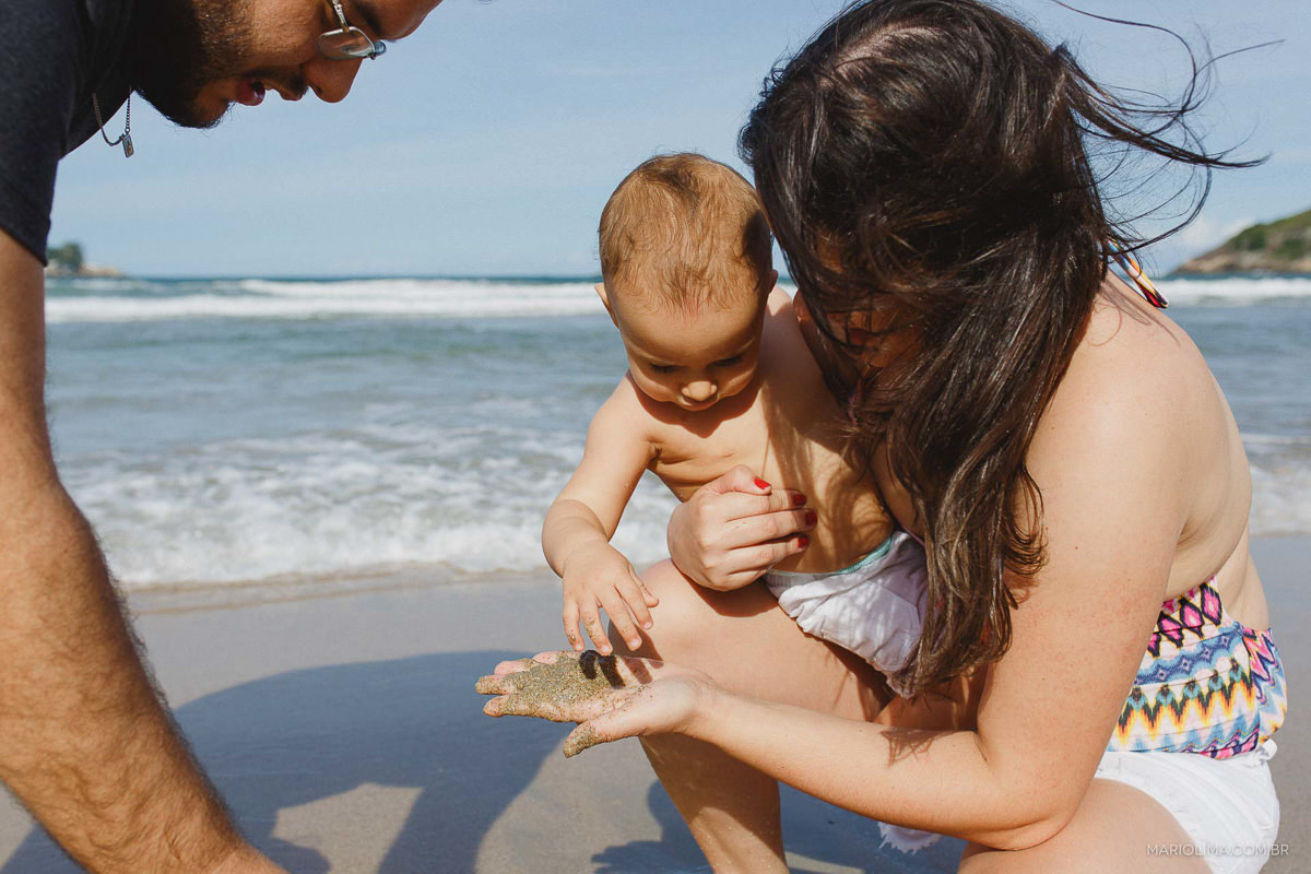 Mãe mostrando areia para o bebê em praia do Guarujá