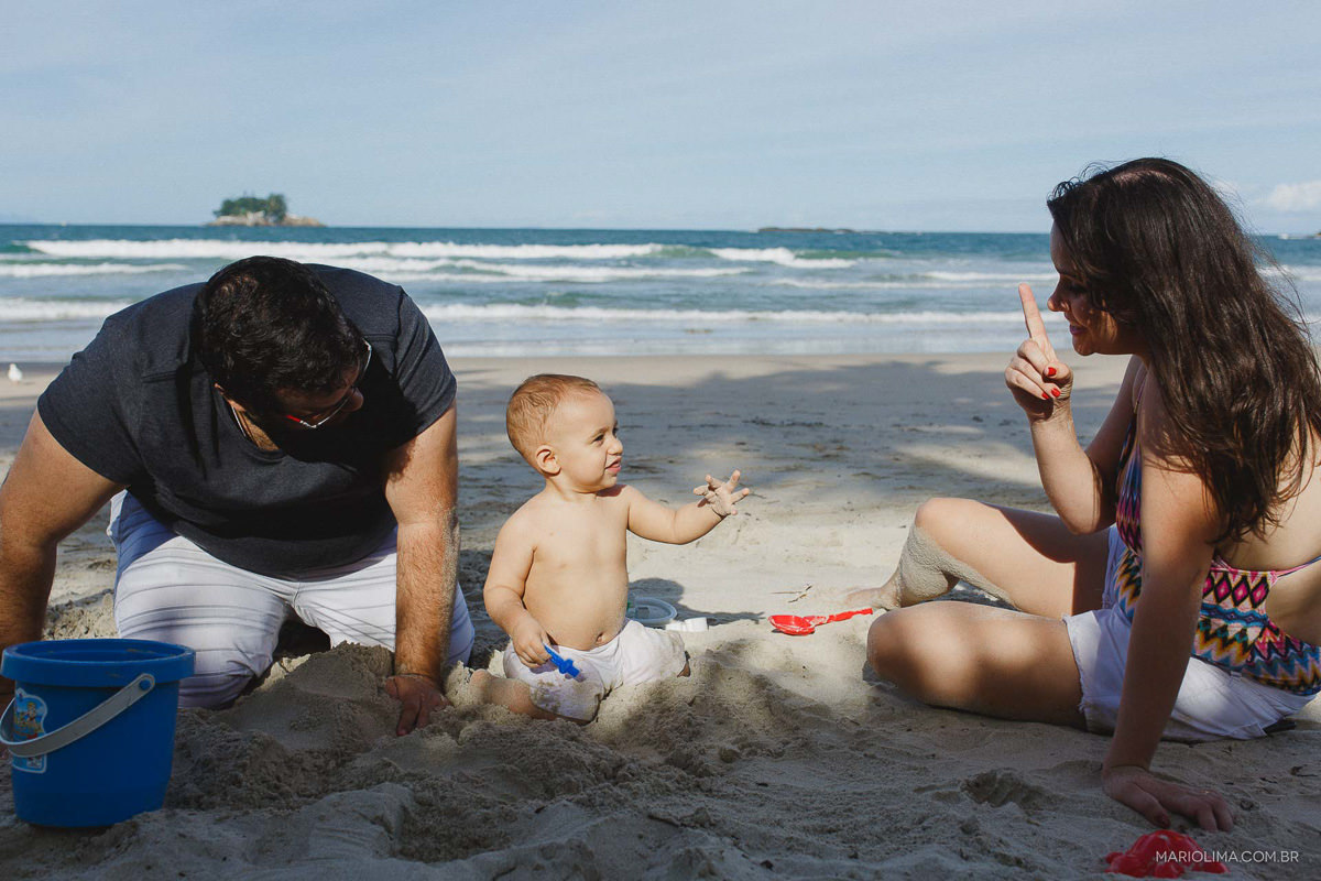 Pai e màe sentados na areia brincando com bebê