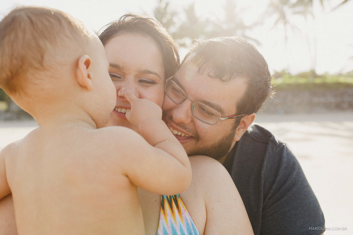Bebê com o dedo no nariz da mãe e pais sorrindo
