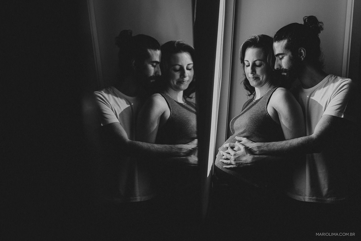 Fotografia de pais em frente ao espelho acarinhando a barriga