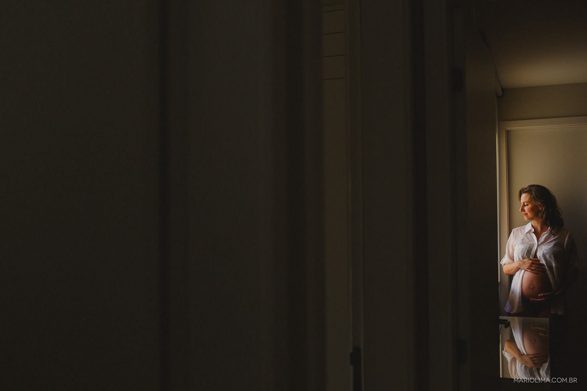 Gravida olhando pela janela e acarinhando a barriga