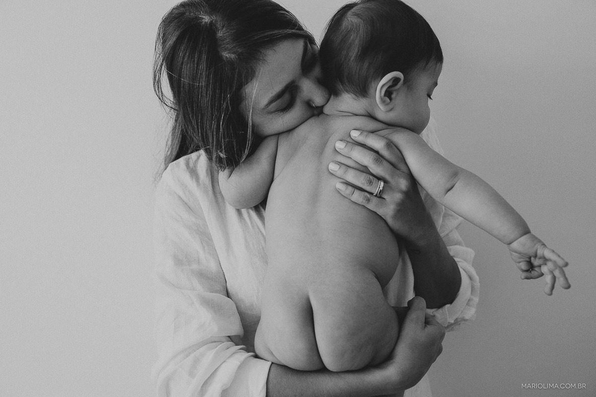 Fotografia de mãe beijando o pescoço do bebê