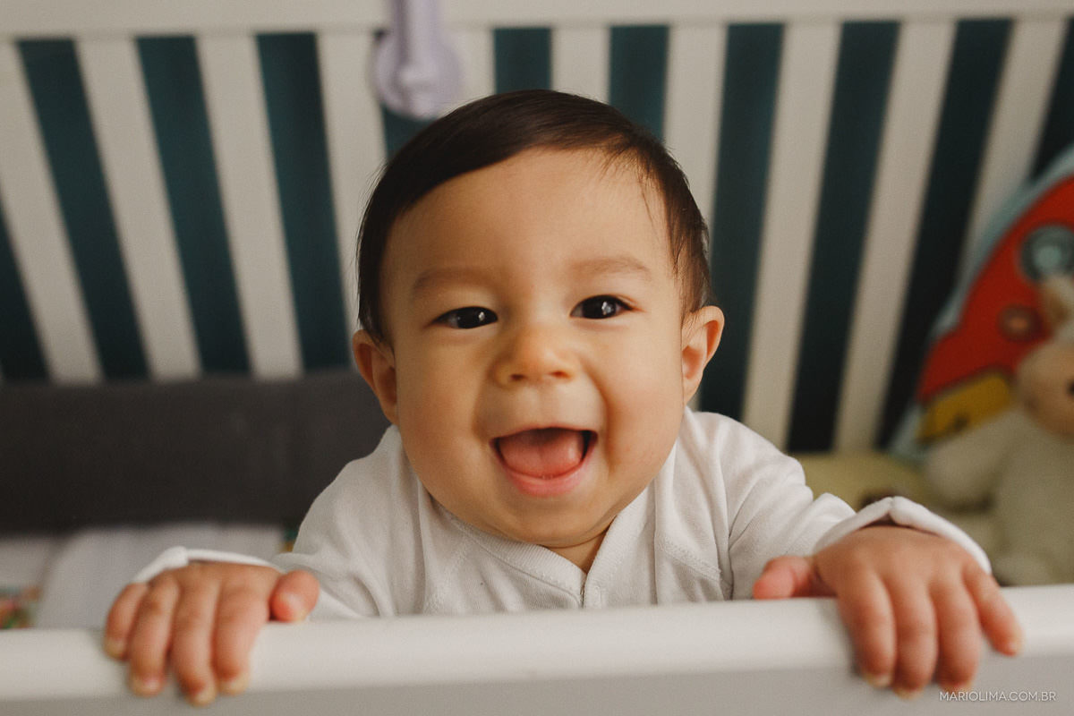 Fotografia de criança em pé, sorrindo no berço
