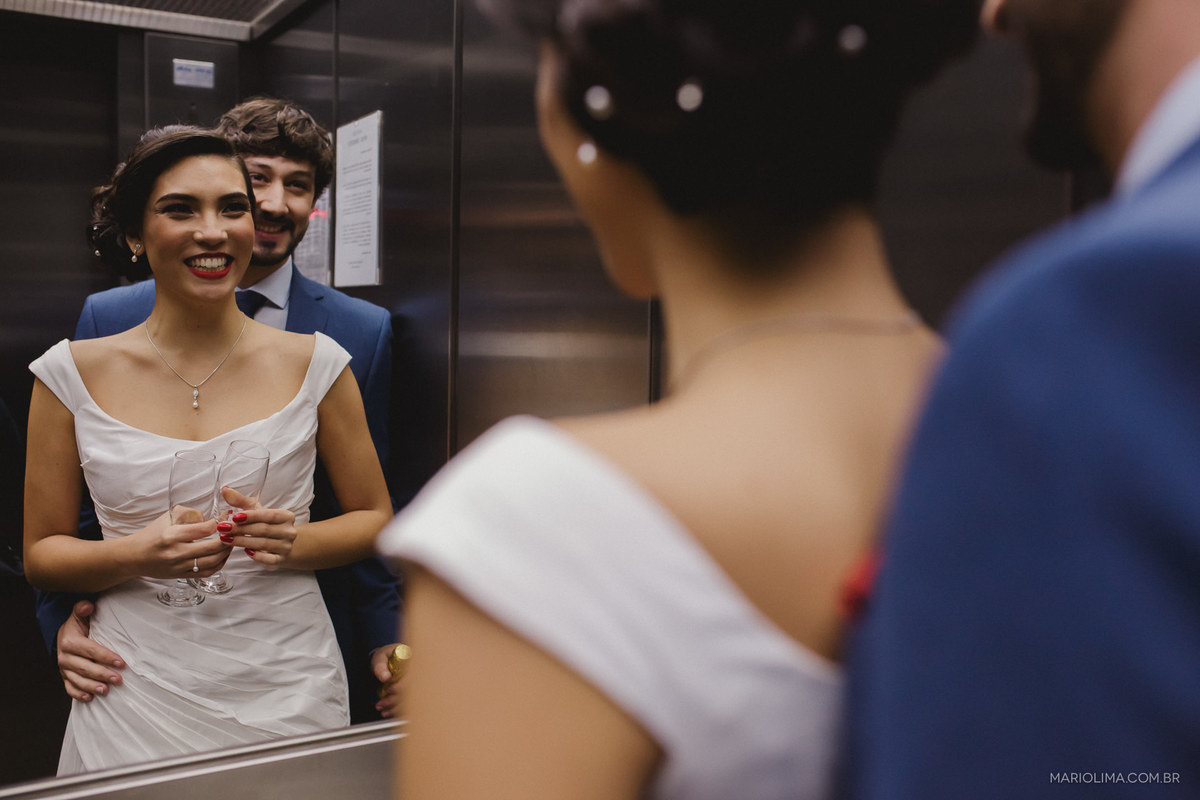Noivos abraçados se olhando no espelho do elevador