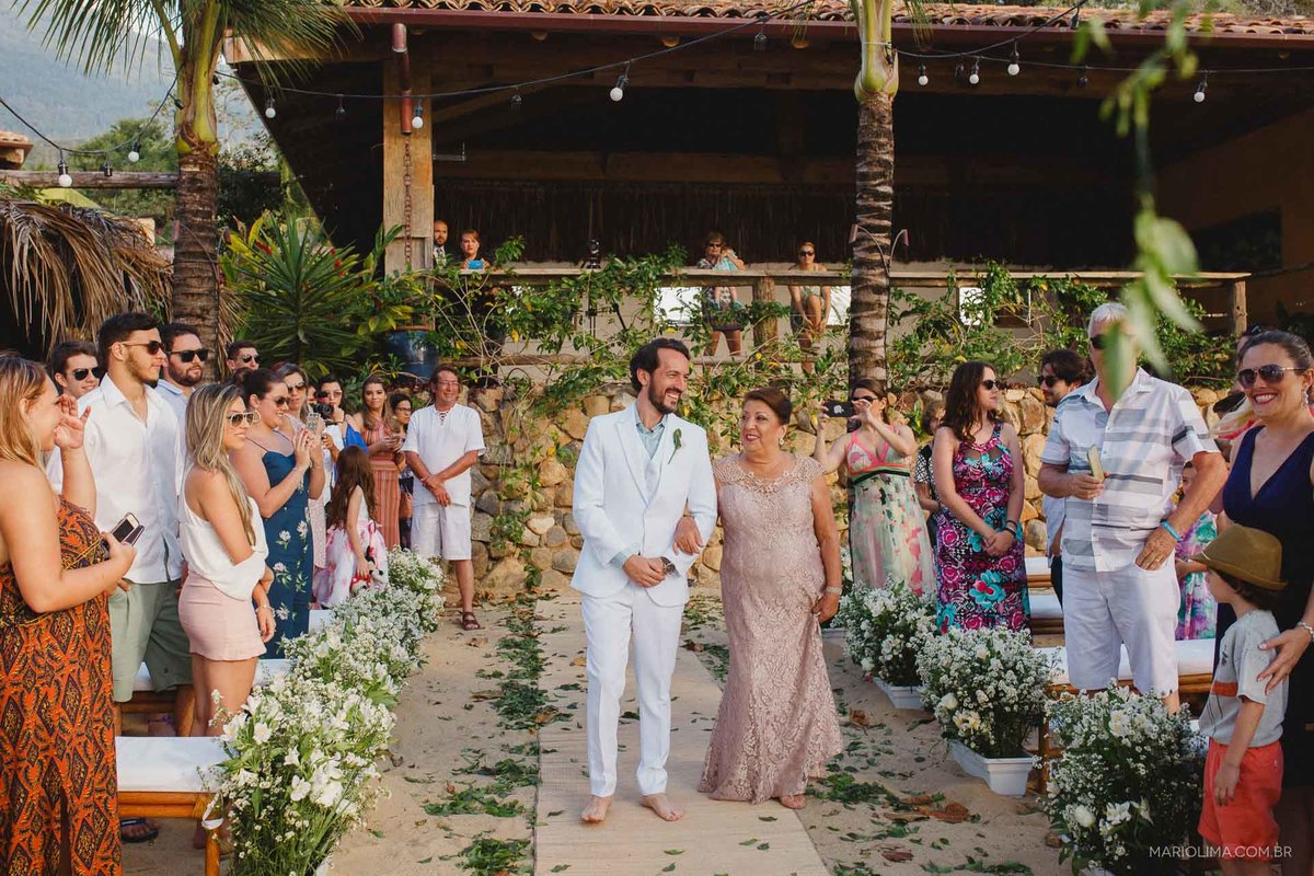 Mãe entrando com o noivo em cerimônia de casamento em Ilha Bela na Vila Salga