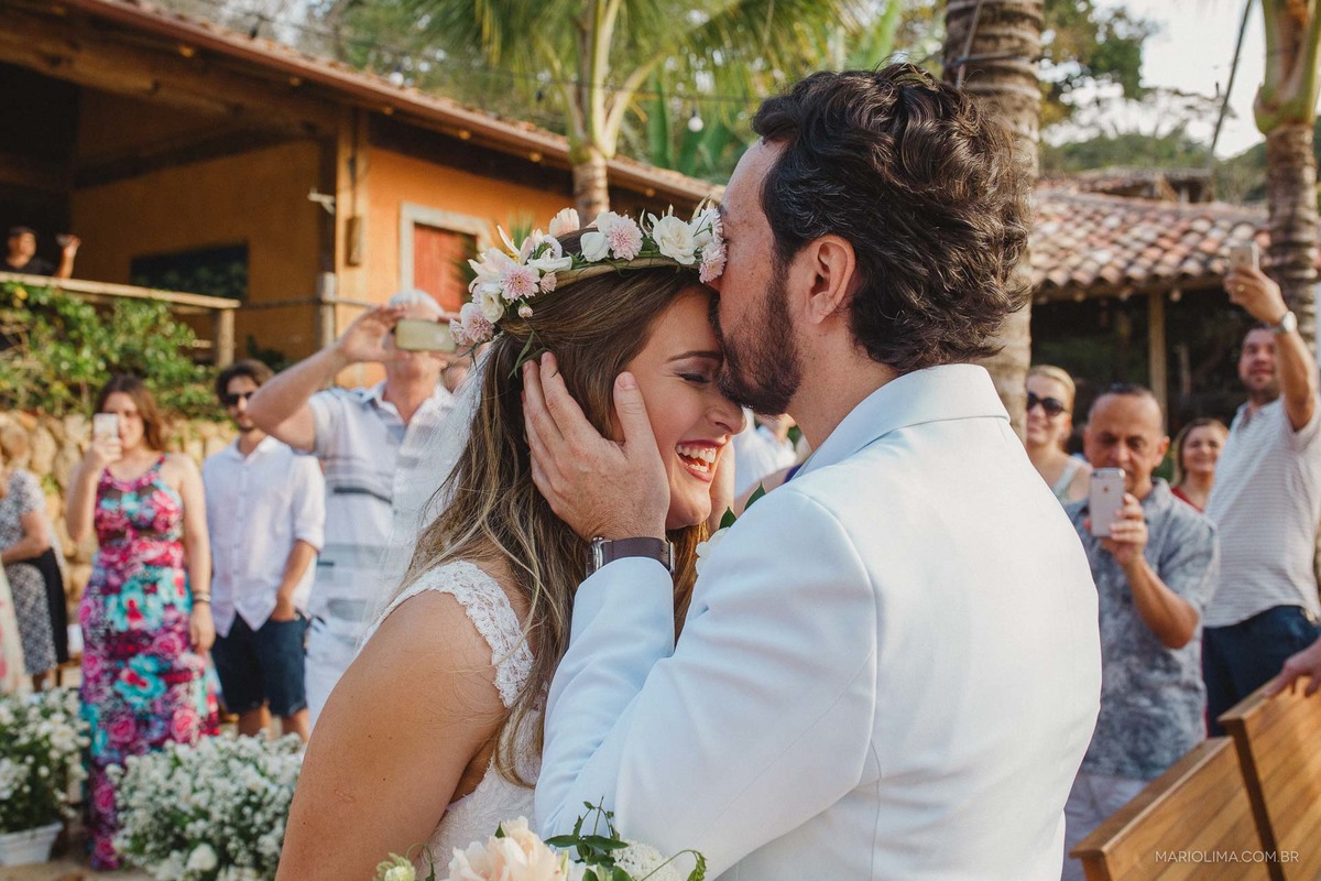 Noivo beijando a testa da noiva em cerimônia de casamento em Ilha Bela na Vila Salga