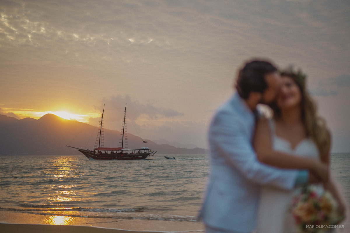 Noivo abraçando e bejiando a noiva na praia de  Ilha Bela na Vila Salga