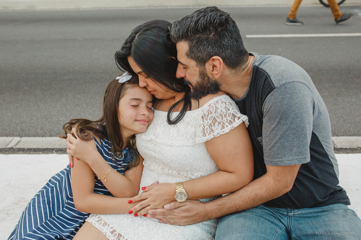 Fotografia de pais abraçando a filha com os olhos fechados no Centro de Sao Paulo