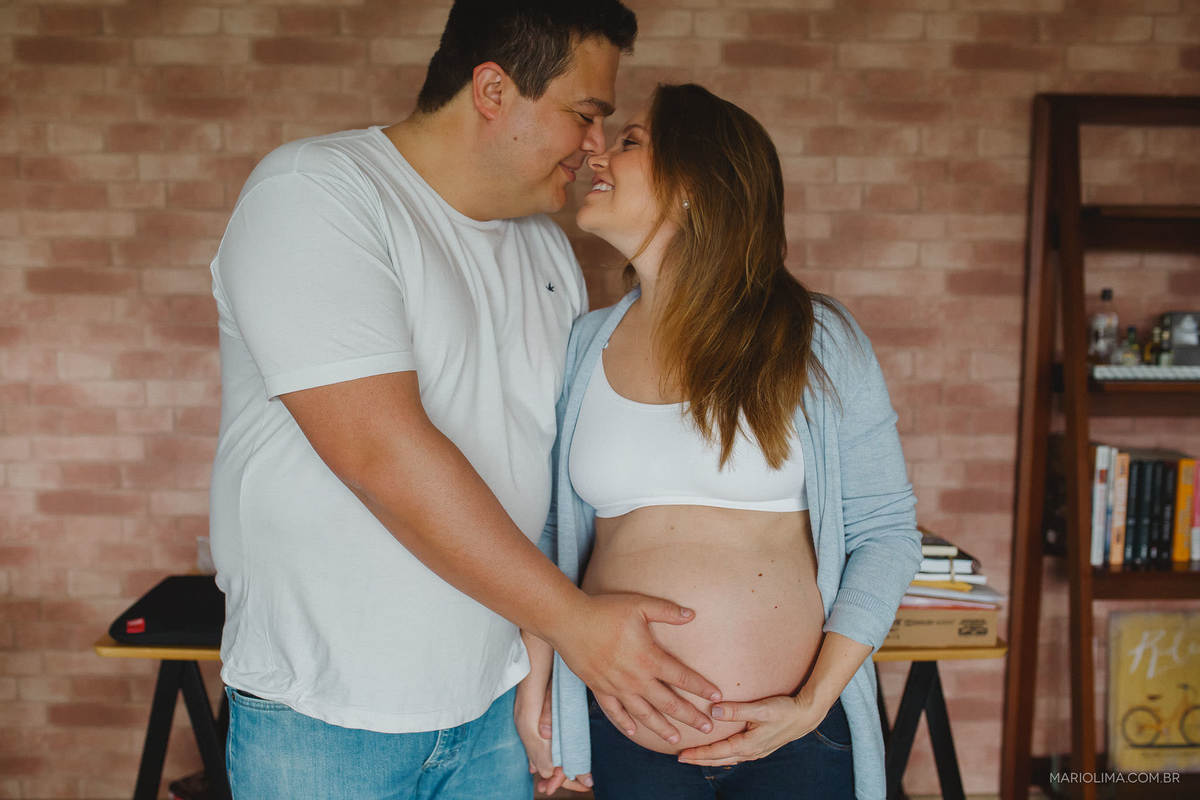 Fotografia de pais com a mão na barriga e narizes encostados