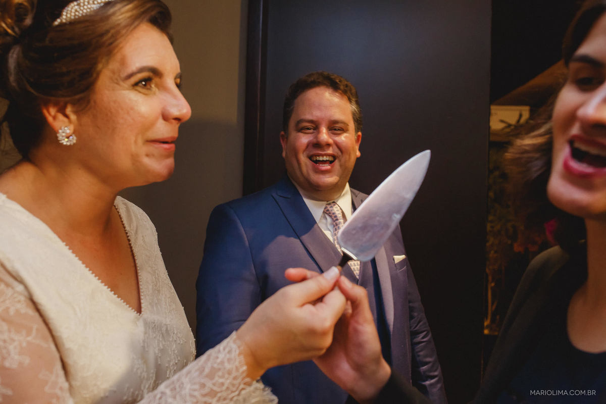 Noiva apontando a espatula de bolo para madrinha e noivo rindo