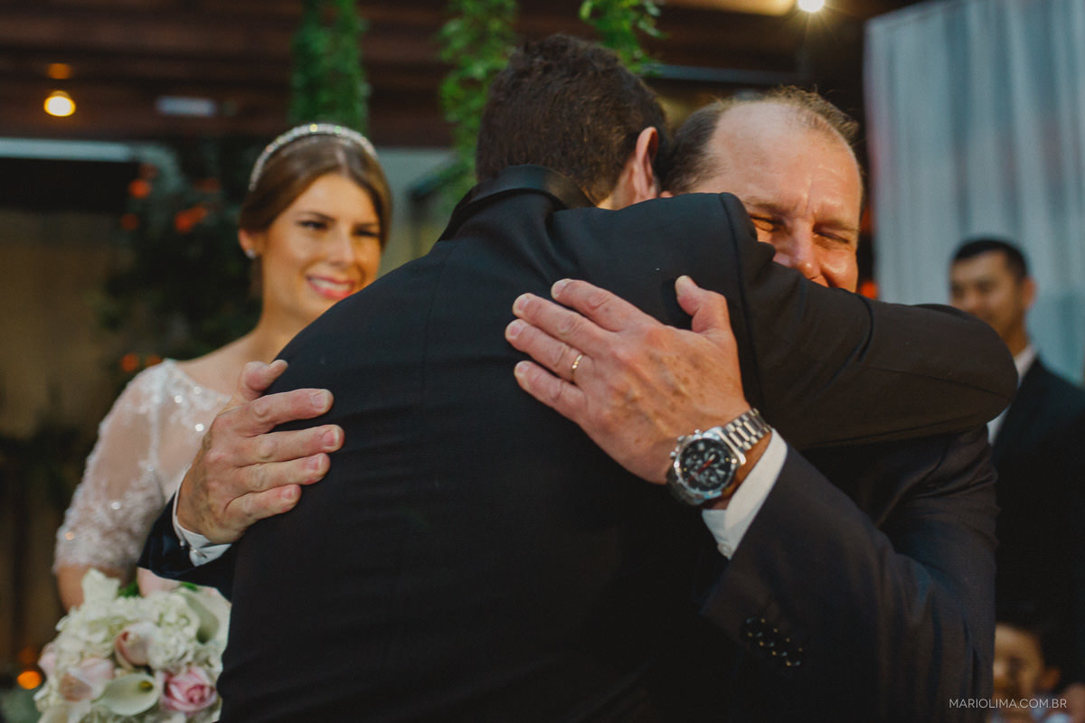 Pai da noiva abraçando o noivo em cerimônia de casamento no Espaço Lilló