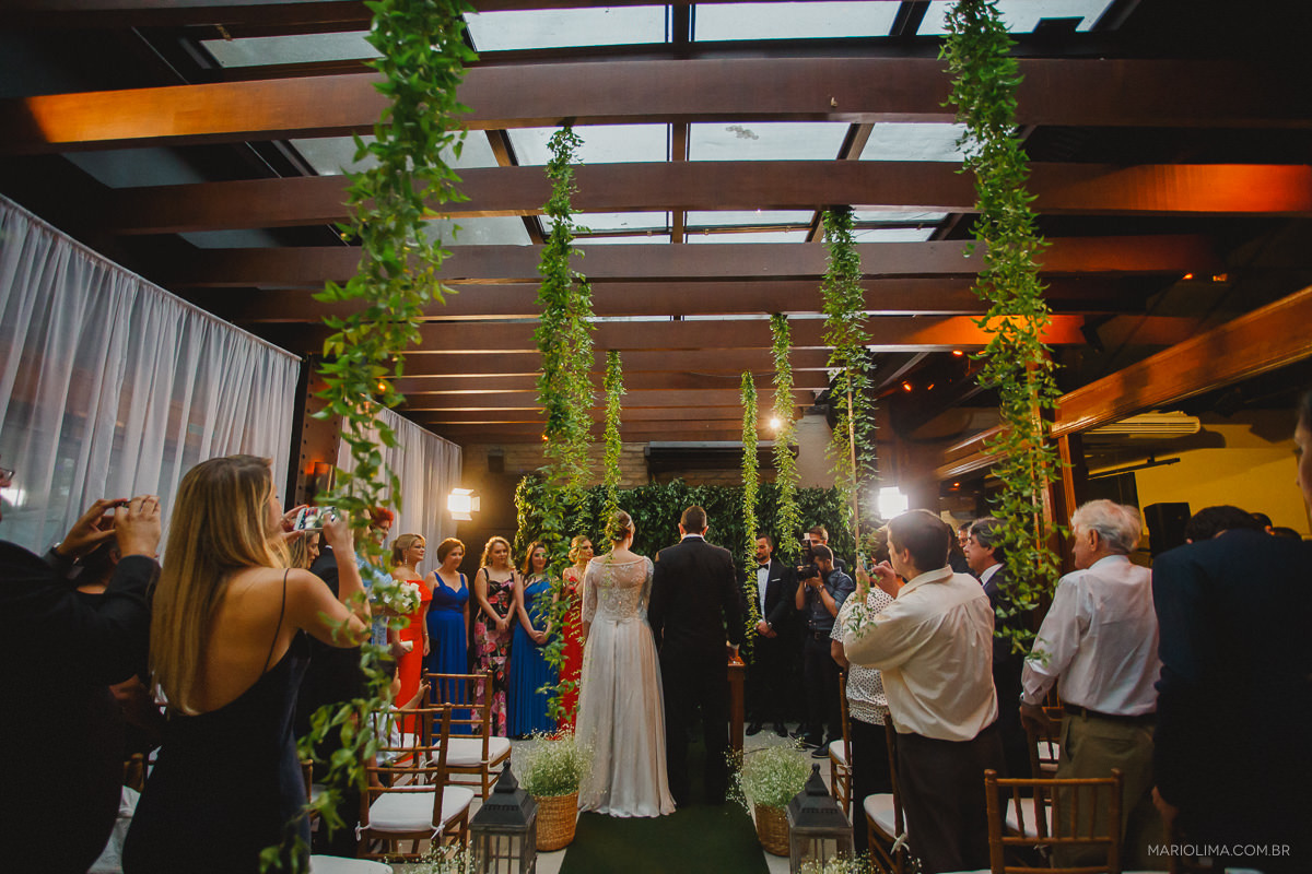 Padrinhos e convidados assistindo a celebração do casamento no Espaço Lilló