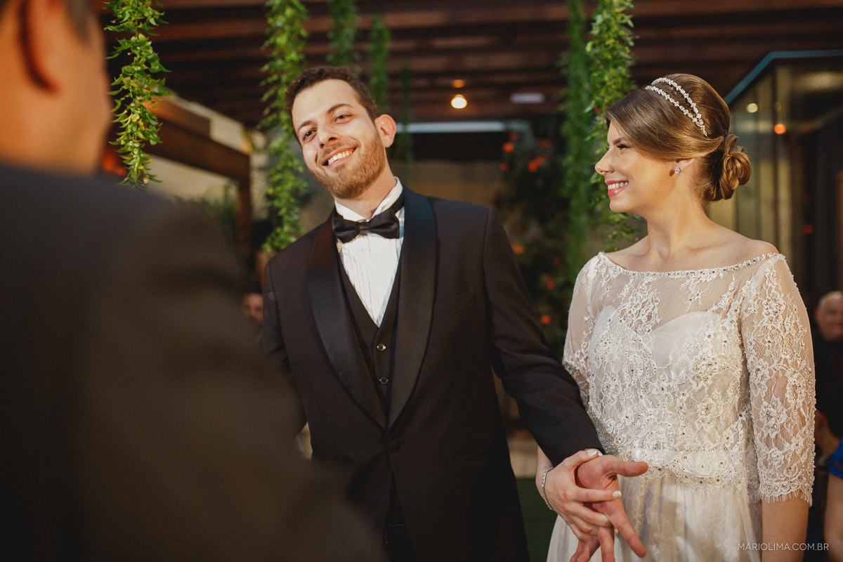 Noivo segurando a mão da noiva em celebração de casamento no Espaço Lilló