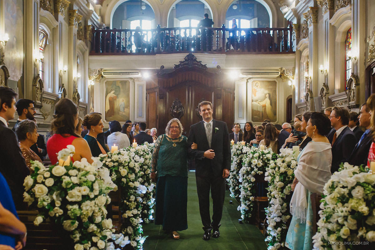 Noivo entrando com a mãe em cerimônia de casamento na Capela da PUC