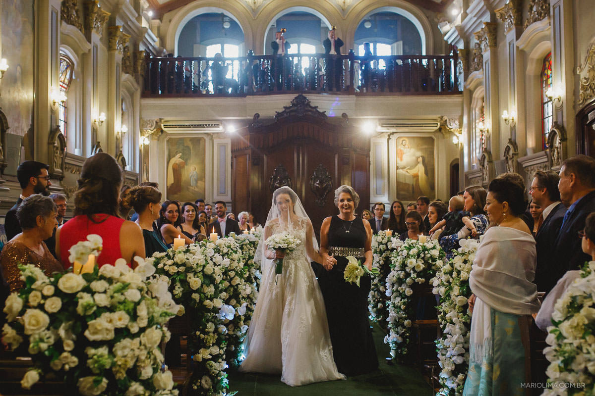 Noiva entrando com a mãe em cerimônia de casamento na Capela da PUC