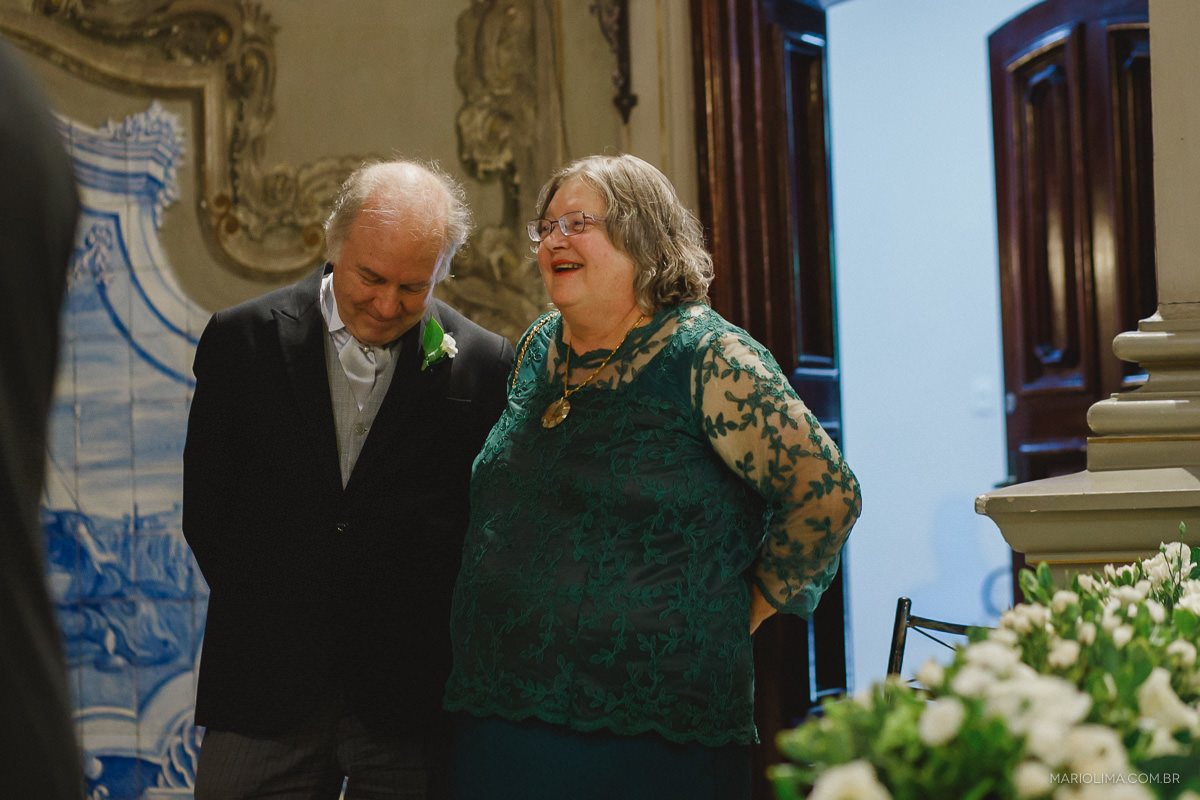 Fotografia dos pais do noivo sorrindo em Capela da PUC
