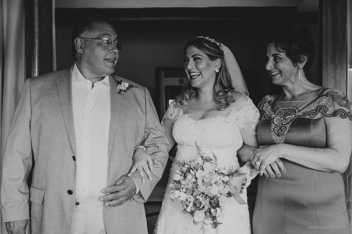 Noiva feliz acompanhada dos pais para cerimônia de casamento em Vila das Velas