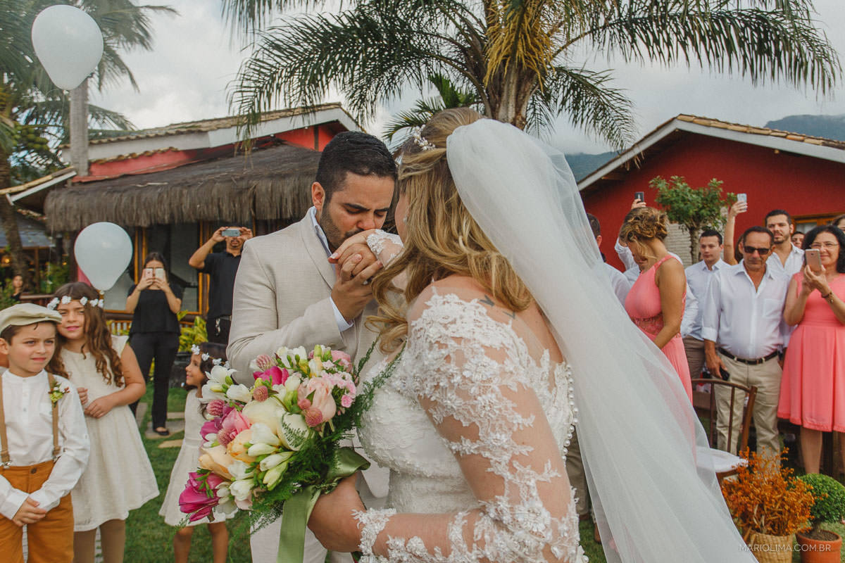Noivo beijando a mão da noiva em cerimônia de casamento na Vila das Velas