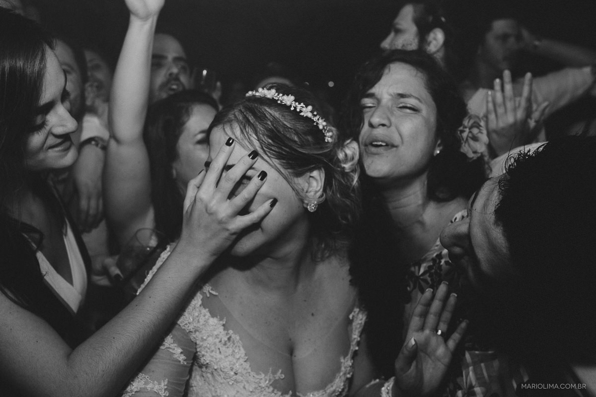 Madrinha com a mão no rosto da noiva em festa de casamento 