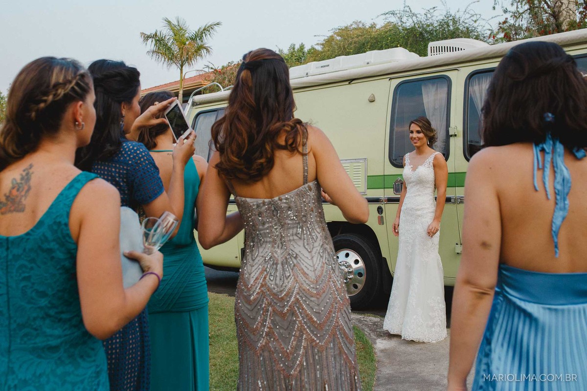 Madrinhas fotografando noiva em frente ao ônibus