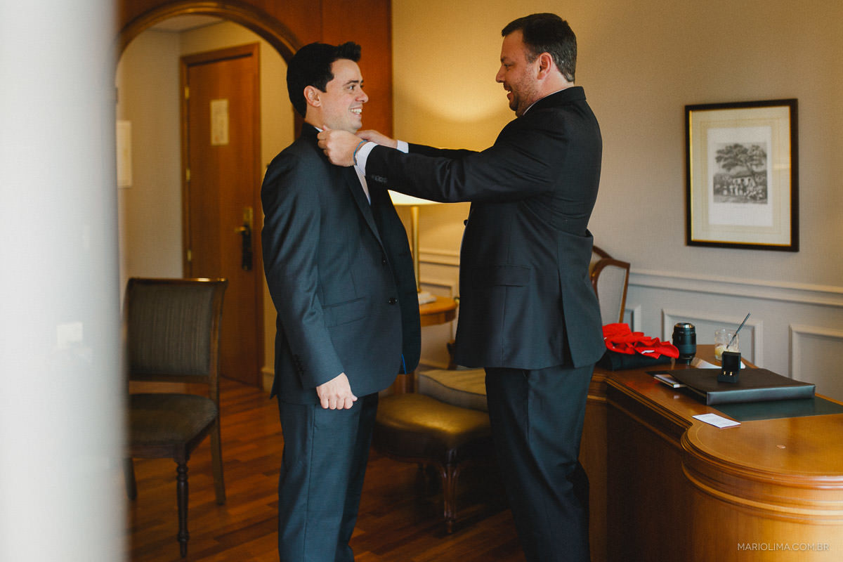 Fotografia de irmão arrumando o terno do noivo