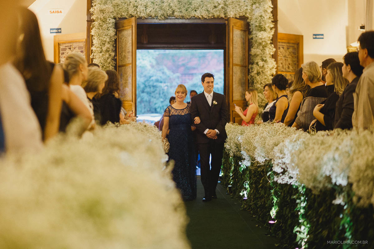 Noivo entrando com a mãe em cerimônia de casamento na Igreja São José do Jardim Europa