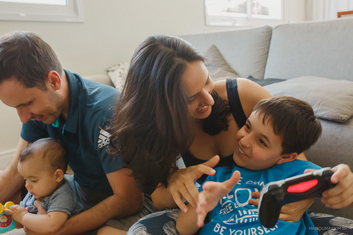 Retrato de pai segurando filho e mãe jogando video game com outro filho