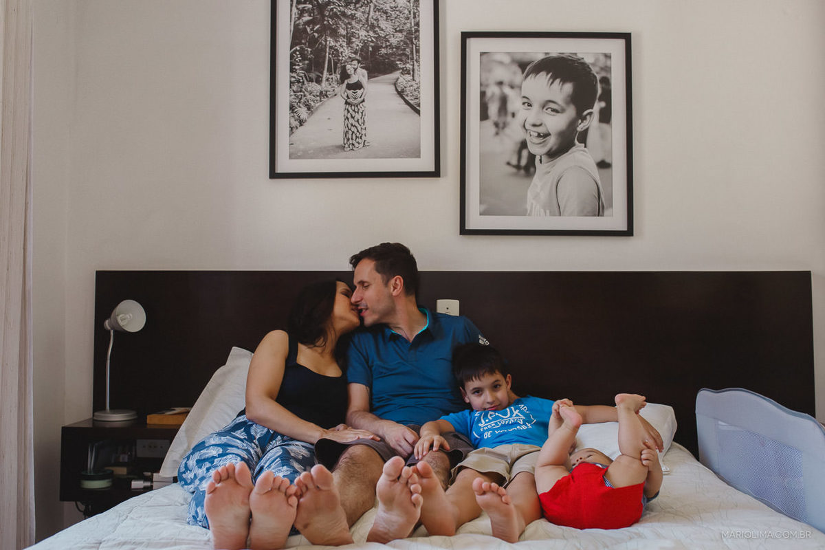 Pais se beijando e filhos brincando na cama