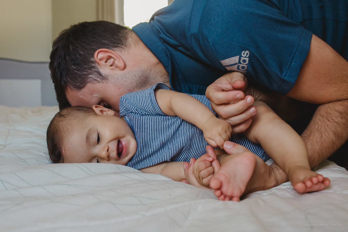 Pai brincando com o filho na cama.
