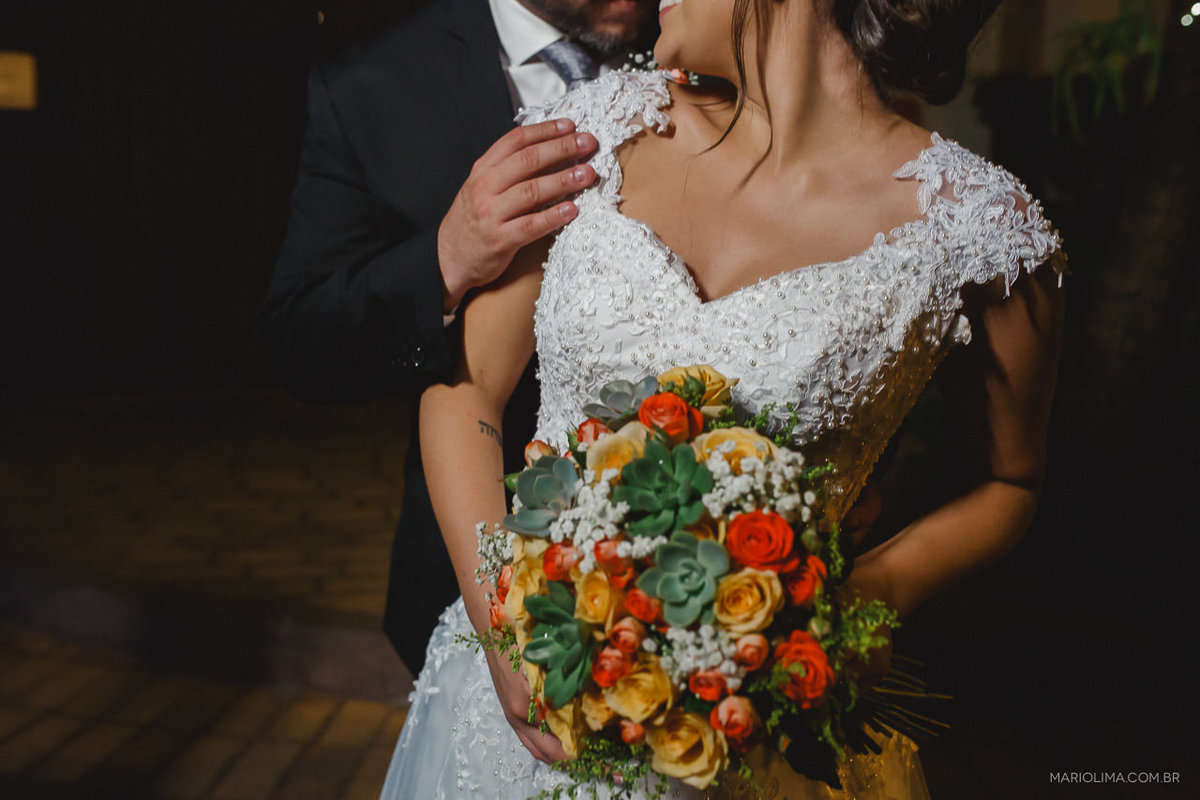 Retrato de noivos abraçados segurando bouquet