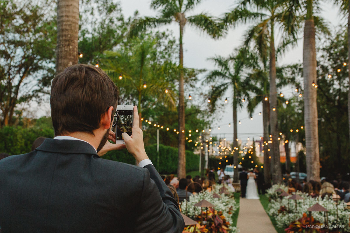 Padrinho fotografando a saída dos noivos em Buffet O Casarão Catanduva