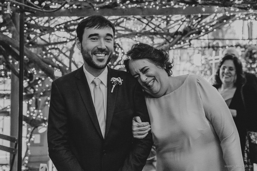 Mãe sorrindo entrando com o noivo em cerimônia de casamento no Espaço Quintal