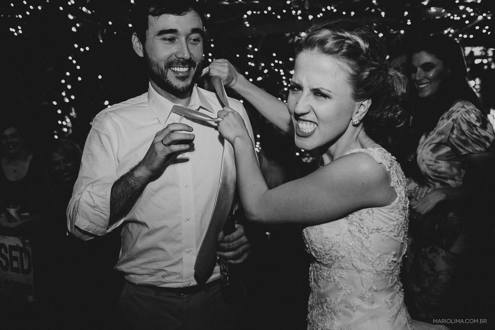 Noiva apertando a gravata do noivo em festa de casamento no Espaço Quintal