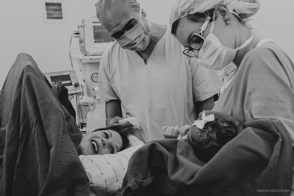 Fotografia de enfermeira segurando a neném para os pais ver