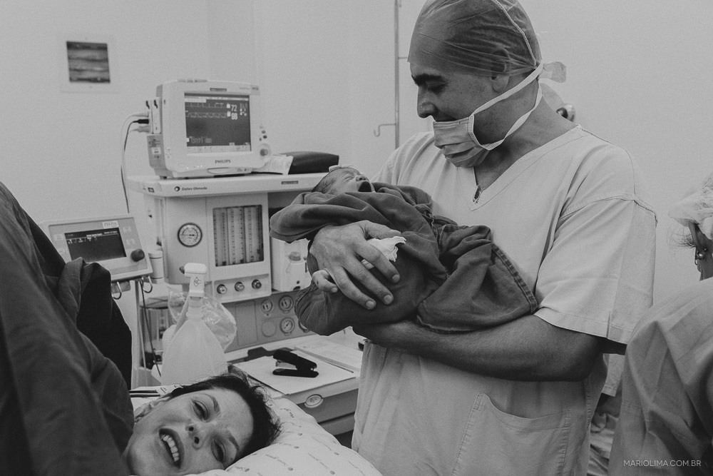 Pai segurando a neném no colo pela primeira vez na sala de parto