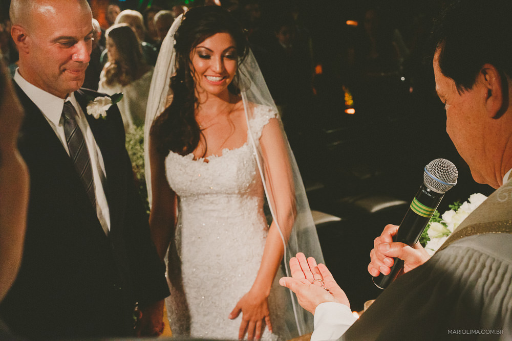 Padre abençoandoas alianças dos noivos em cerimônia de casamento