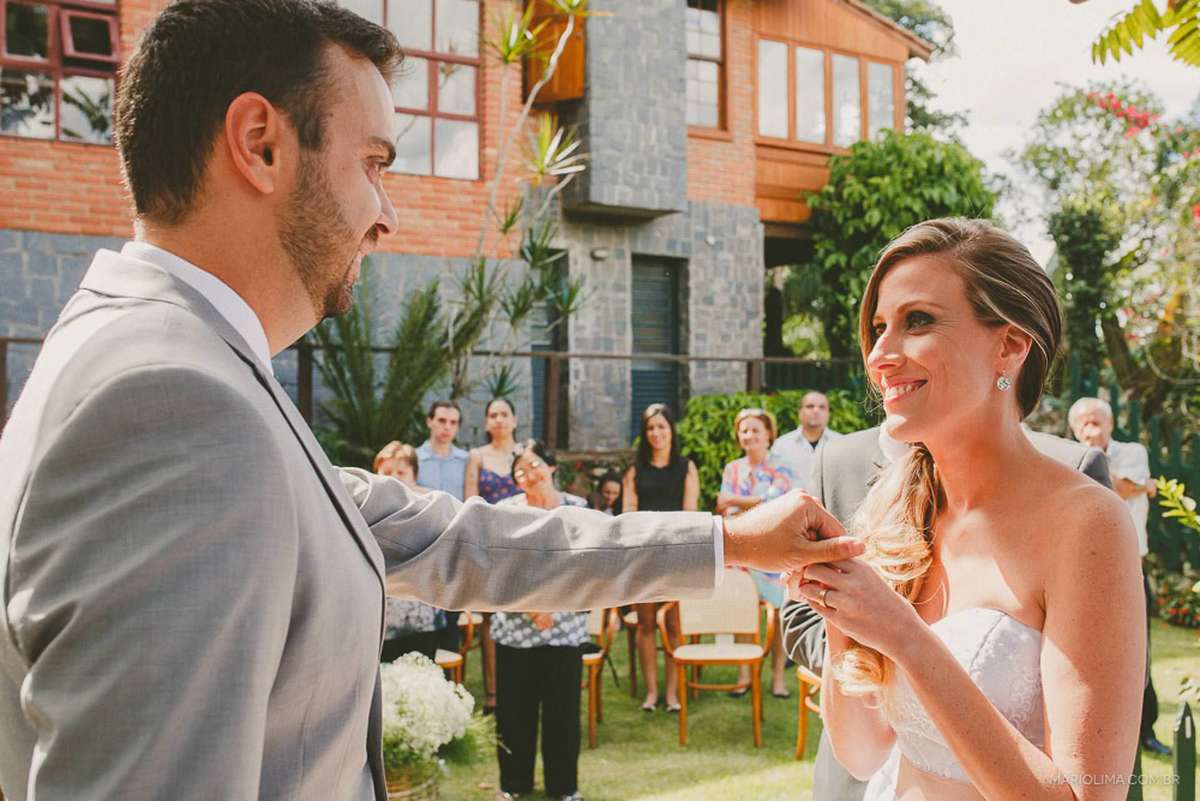 Noiva colocando aliança na mão do noivo em cerimônia de casamento na Quinta da Cana