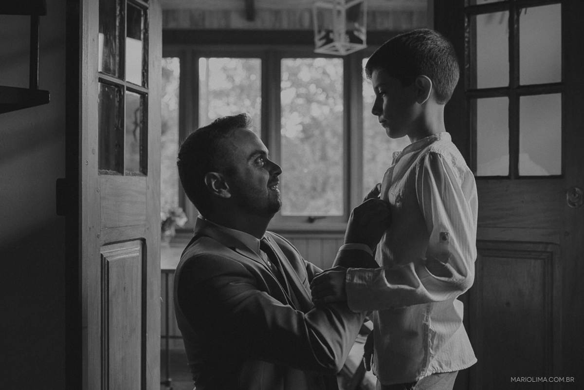 Fotografia de noivo ajudando enteado com camisa no making of