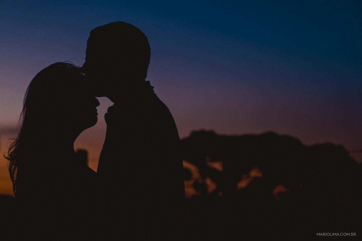 Homem beijando a testa da mulher no pôr do sol