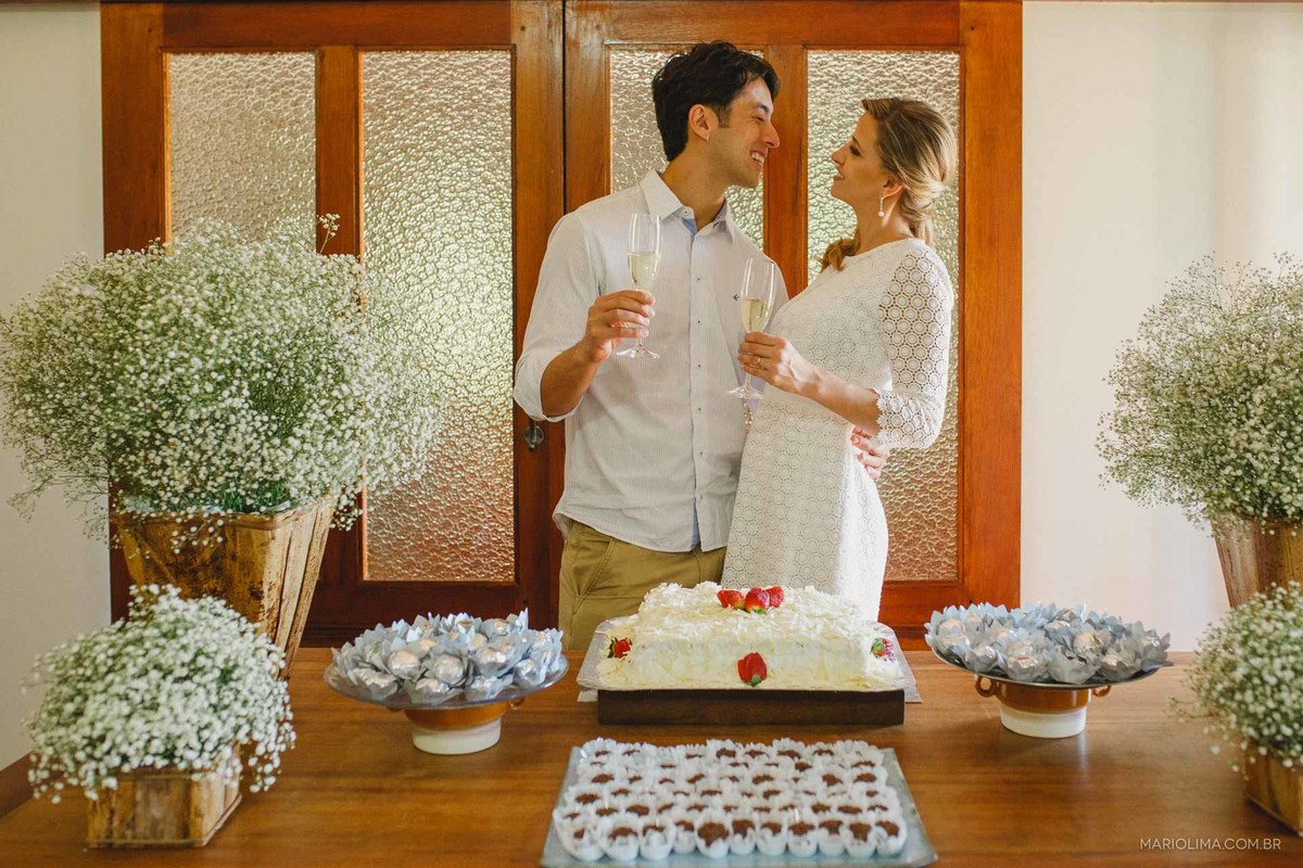 Fotografia de noivos bebendo champagne na mesa do bolo em festa de casamento