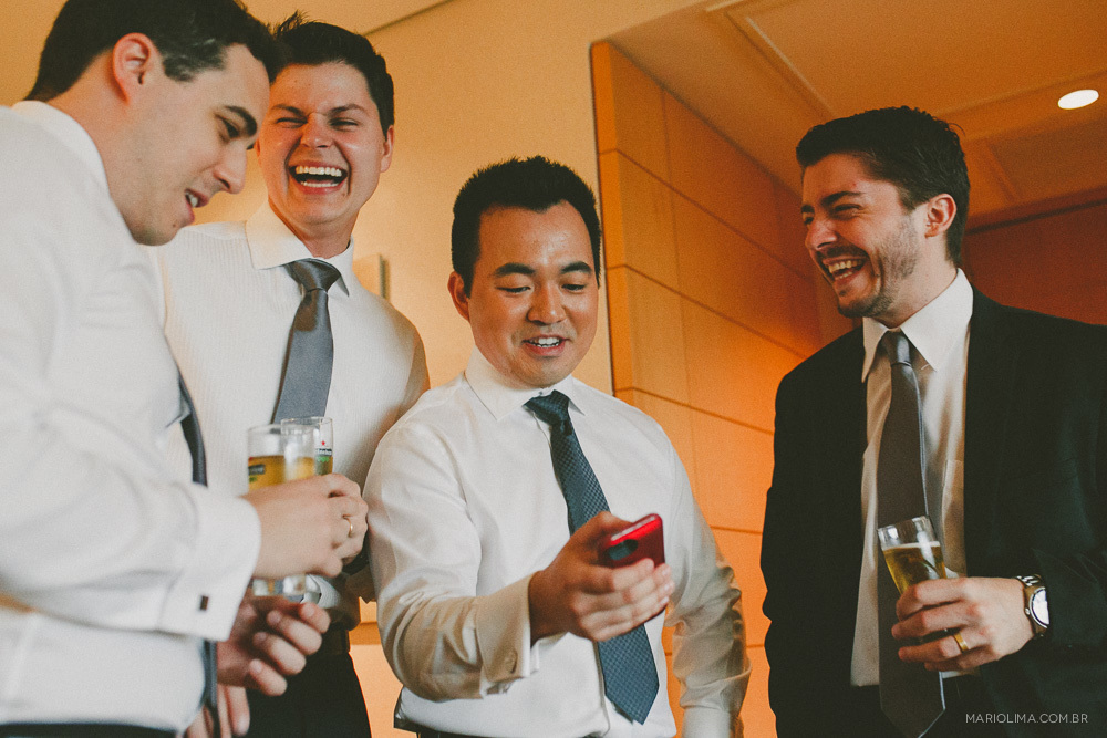 Fotografia de noivo mostrando mensagem no celular para os padrinhos