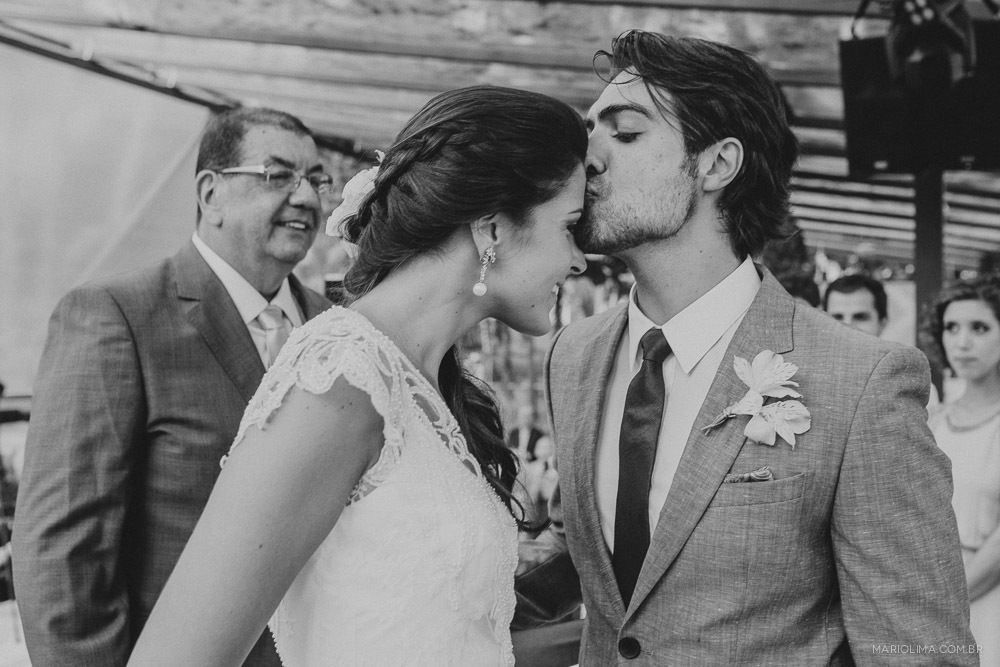 Noivo beijando a testa da noiva em cerimônia de casamento no Juquehy