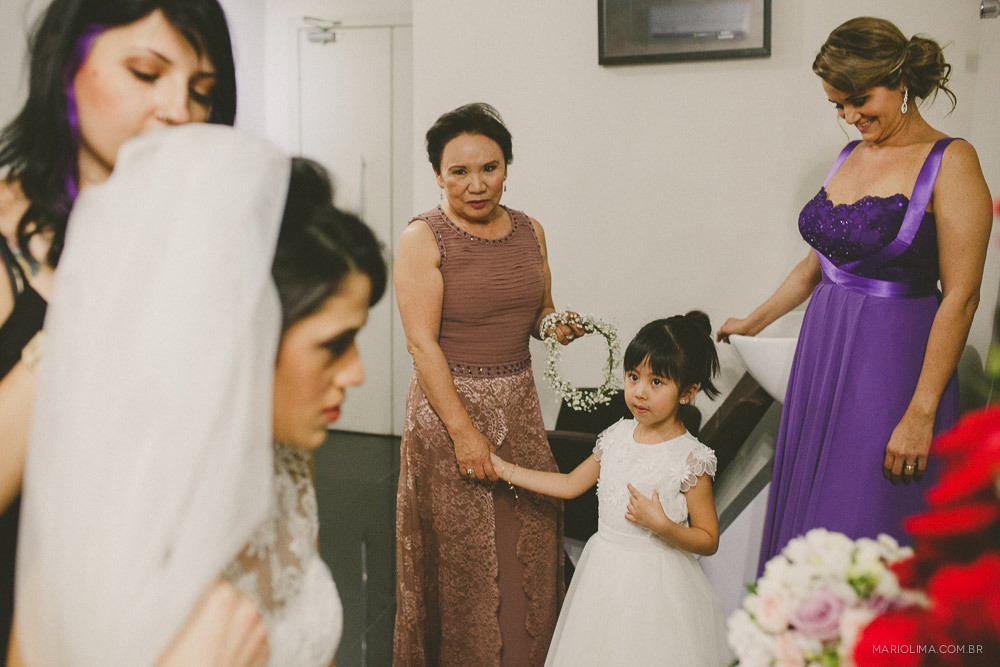 Cabeleireira colocando o véu na noiva e daminha olhando