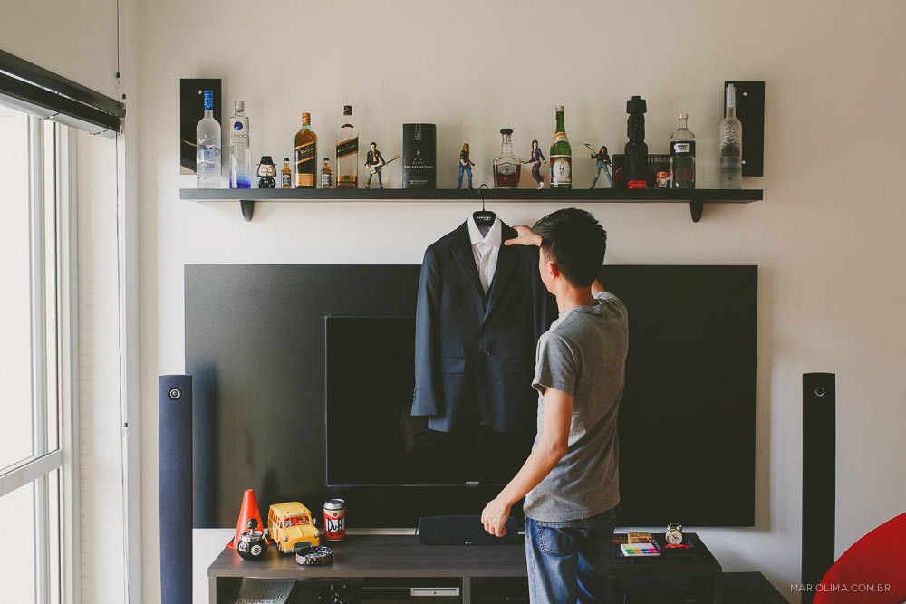 Retrato de noivo olhando para o terno no making of