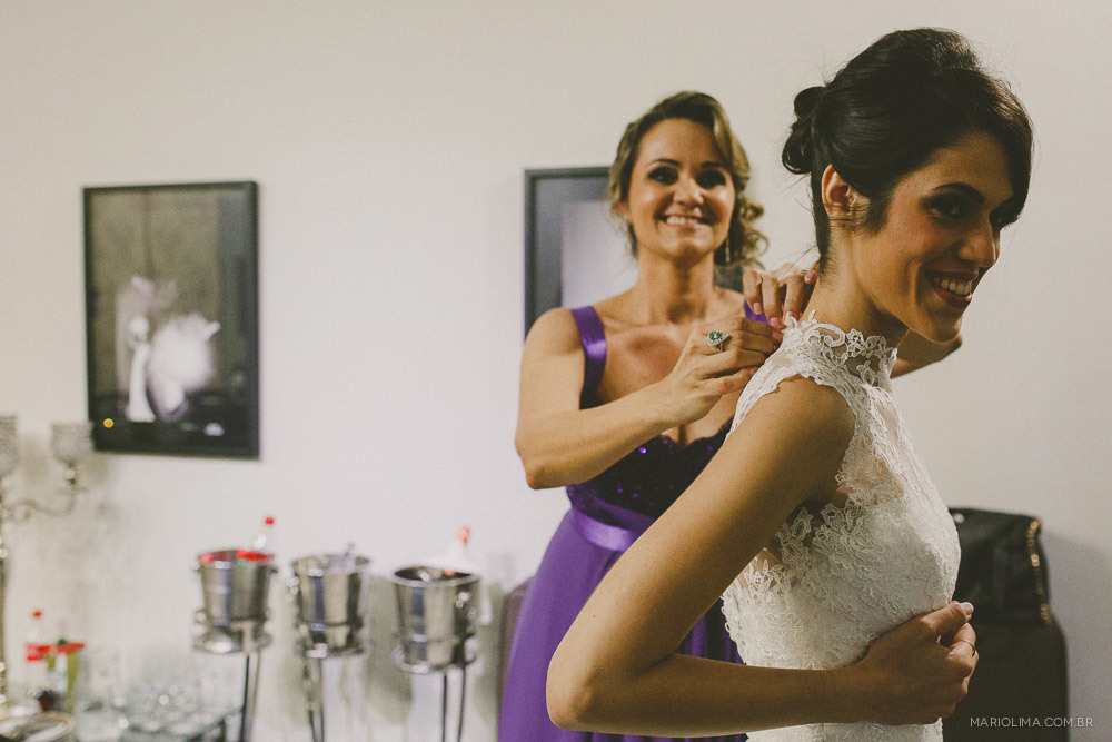 Madrinha ajudando a noiva a abotoar o vestido