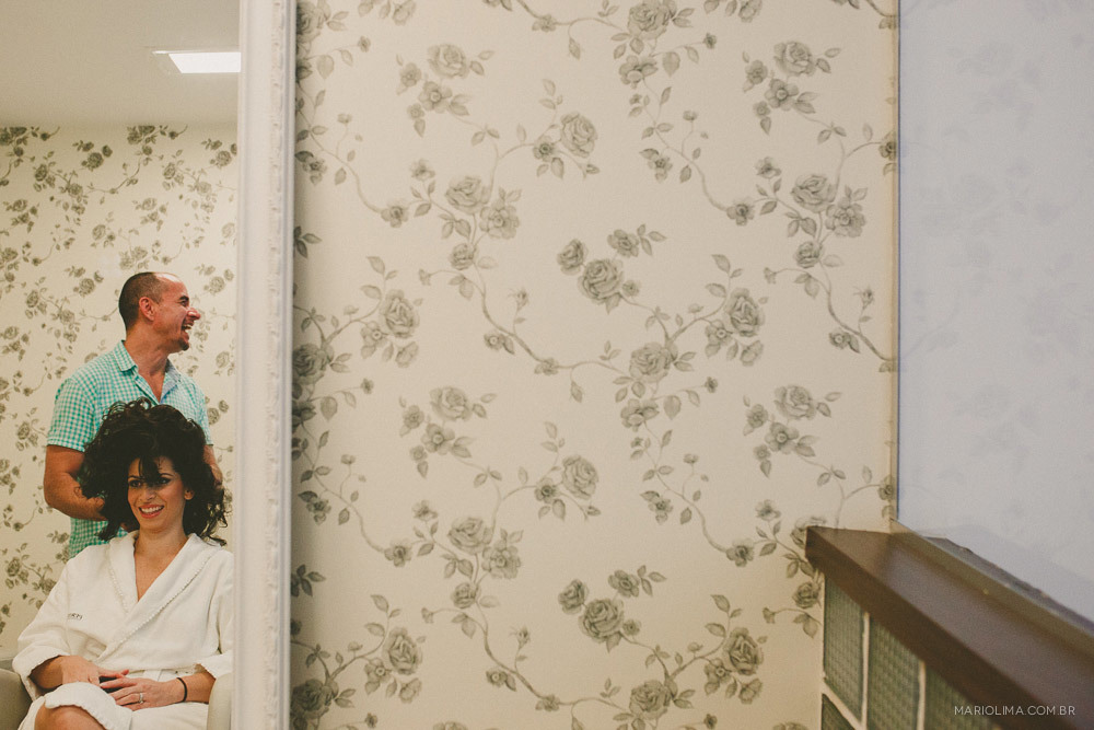 Fotografia de cabeleireiro arrumando a noiva no making of